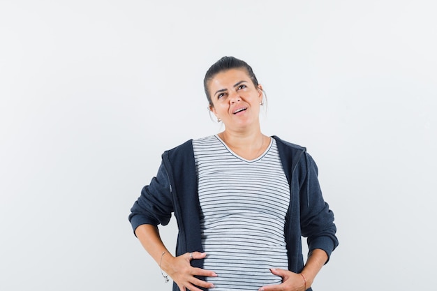 Donkerharige vrouw met hand op haar buik in shirt