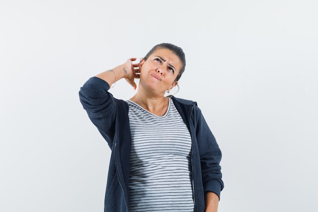 Donkerharige vrouw met hand op nek terwijl wegkijken in shirt