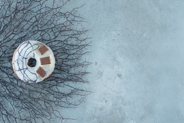 Donut geplaatst op een bos van gedroogde takken op marmeren achtergrond. Hoge kwaliteit foto