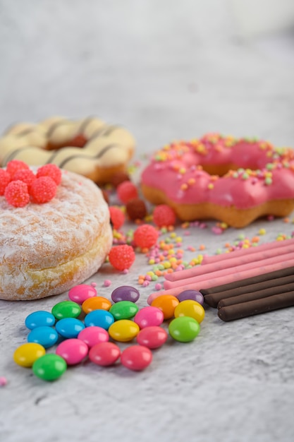 Donuts bestrooid met poedersuiker en snoep op een witte ondergrond.