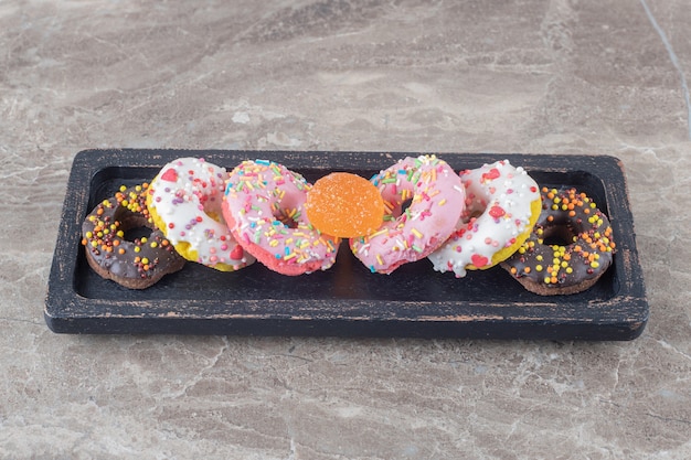 Donuts en een marmelade gebundeld op een zwart dienblad op een marmeren oppervlak