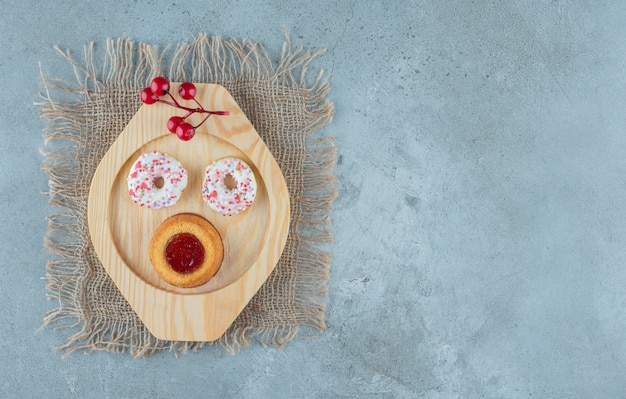 Donuts en een met gelei gevulde cake op een houten schotel op marmeren achtergrond. hoge kwaliteit foto