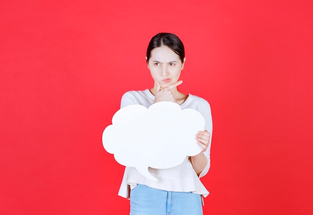 Doordachte jonge vrouw met tekstballon met de vorm van een wolk