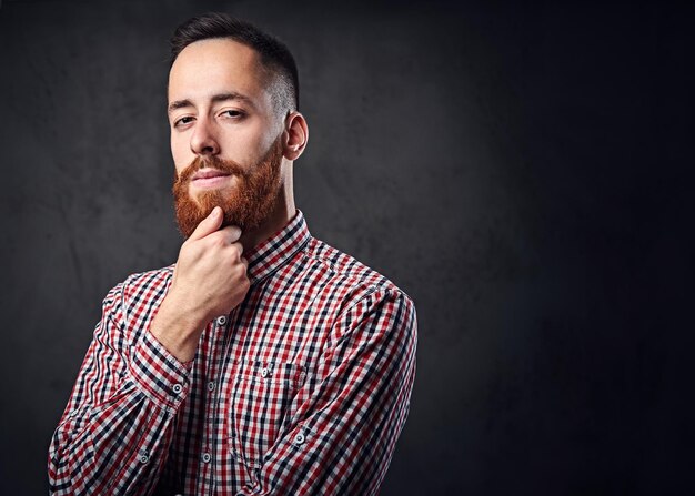 Doordachte roodharige bebaarde hipster man gekleed in een rood fleece shirt.