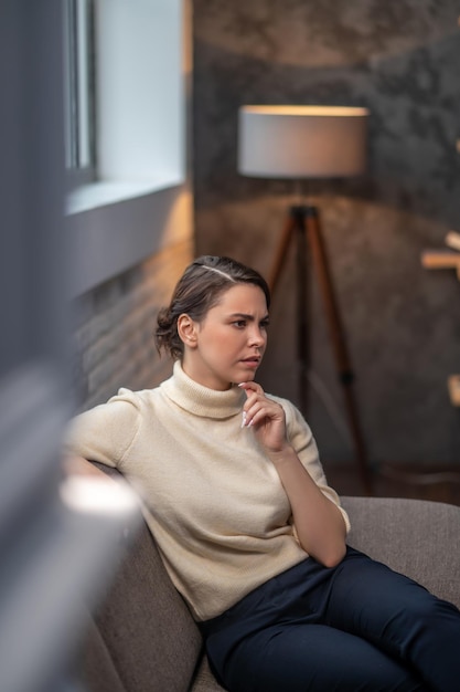 Gratis foto doordachte vrouw zittend in een woonkamer