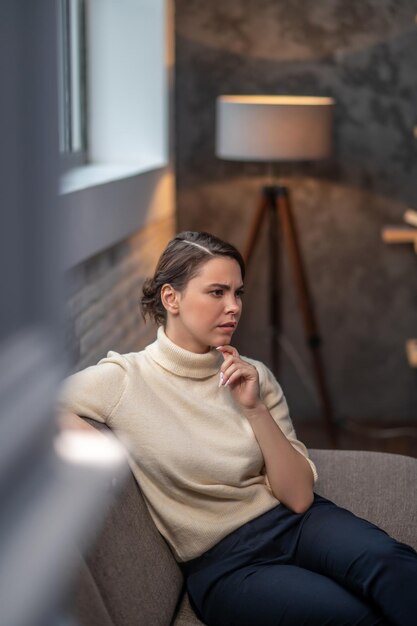 Doordachte vrouw zittend in een woonkamer