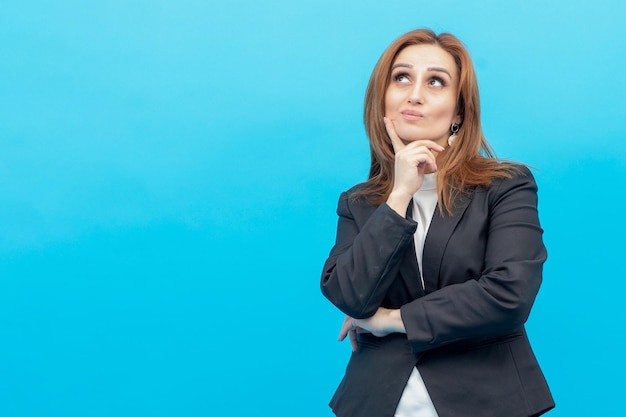 Doordachte zakenvrouw legde haar vinger op haar kin en dacht aan een blauwe achtergrond