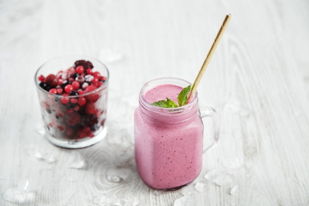 Doorzichtige rustieke pot met smakelijke, gezond vers gemaakte lichtviolette smoothie met rietje erin