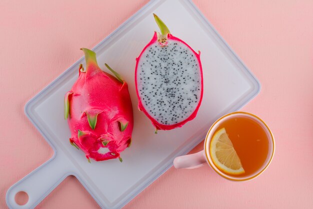 Dragon fruit met thee op roze en snijplank, plat lag.