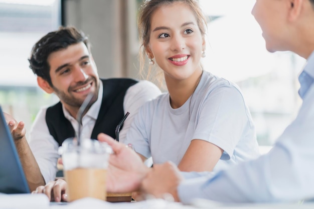 Drie aziatische en kaukasische zakenmensen die werken bespreken het vinden van een nieuwe strategieoplossing samen met laptop in café