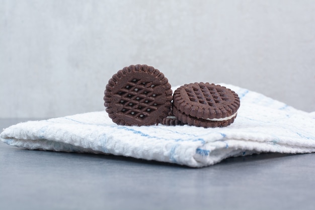 Drie chocoladekoekjes die op tafelkleed liggen.