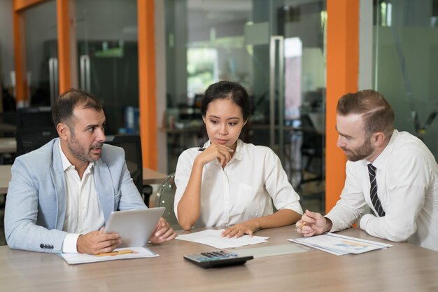 Drie doordachte marketinganalisten die met diagrammen werken