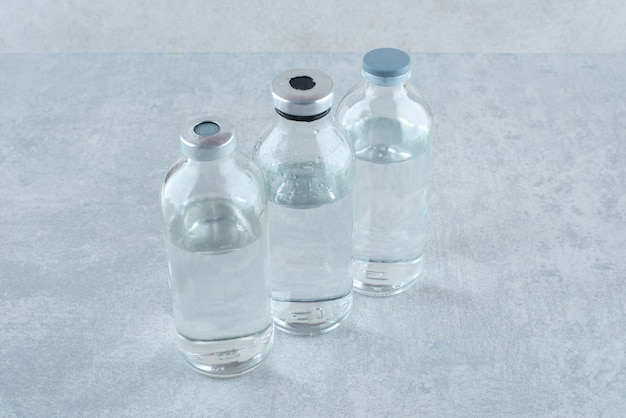Drie flessen medische ethanol op een grijze ondergrond