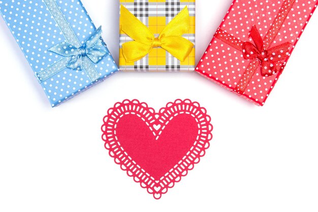 Drie gekleurde geschenkdozen met gesneden papier hart op witte achtergrond bovenaanzicht Premium Foto