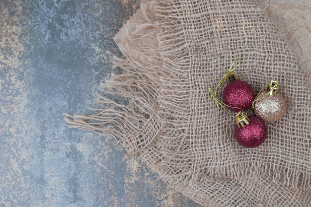 Drie glanzende kerstballen op jute.