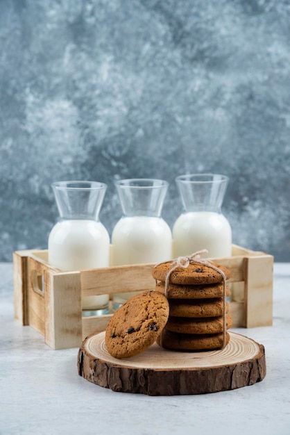 Gratis foto drie glazen pot melk en stapel koekjes op marmeren tafel.