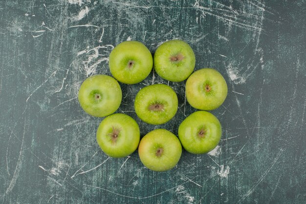 Drie groene appels op marmeren oppervlak.