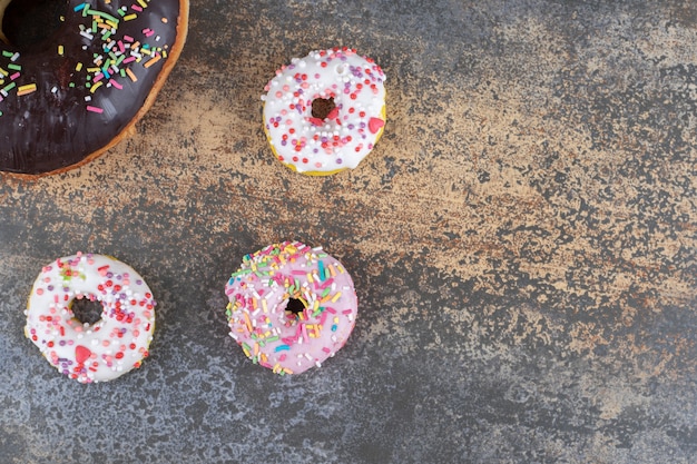 Drie hapklare donuts naast een grote donut op houten oppervlak