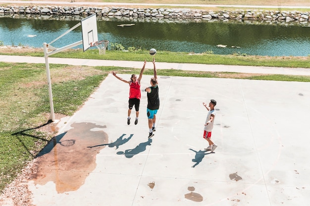 Drie jonge mannelijke speler spelen basketbal