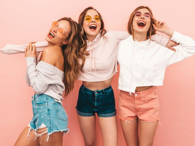 Drie jonge mooie glimlachende meisjes in trendy zomerkleren. Sexy zorgeloze vrouwen poseren. Positieve modellen hebben plezier