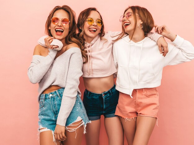 Drie jonge mooie glimlachende meisjes in trendy zomerkleren. Sexy zorgeloze vrouwen poseren. Positieve modellen hebben plezier