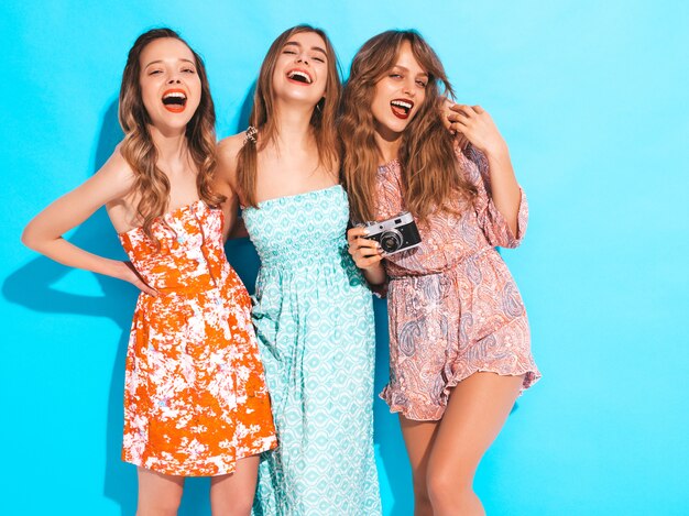 Drie jonge mooie lachende meisjes in trendy zomer casual jurken. Sexy zorgeloze vrouwen poseren. Foto's maken met een retro camera