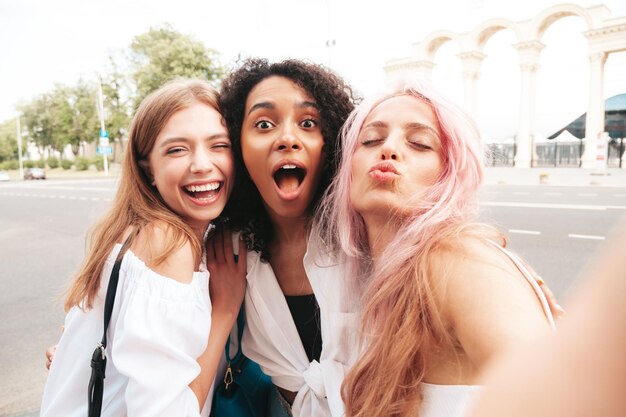 Drie jonge mooie lachende vrouw in trendy zomerkleren Sexy zorgeloze multiraciale vrouwen poseren op de straat achtergrond Positieve modellen plezier in zonnebril vrolijk en gelukkig