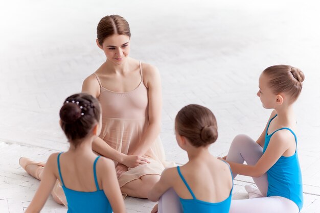 Drie kleine ballerina's dansen met persoonlijke balletleraar in dansstudio