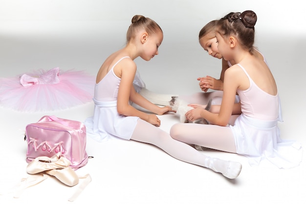 Drie kleine en balletmeisjes die samen zitten stellen