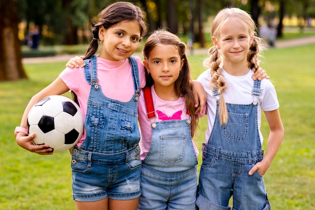 Drie kleine meisjes poseren voor de camera in het park