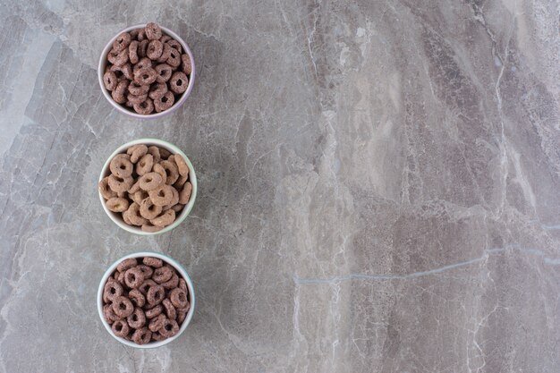 Drie kleurrijke kommen chocoladegranenringen voor ontbijt.