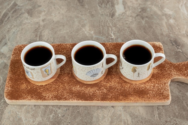 Drie kopjes espresso op een houten bord