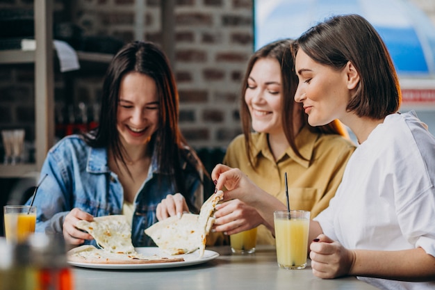 Drie meisjesvrienden die pizza hebben bij een bar