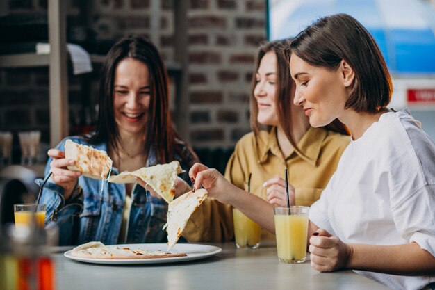 Drie meisjesvrienden die pizza hebben bij een bar