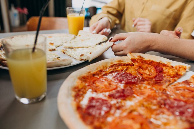 Drie meisjesvrienden die pizza hebben bij een bar