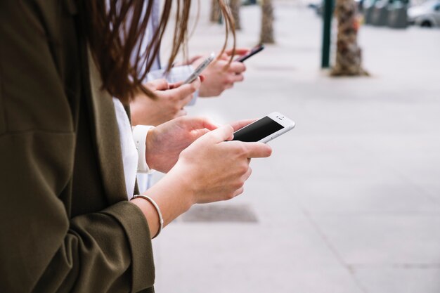 Drie mensen die mobiele telefoon in openlucht gebruiken