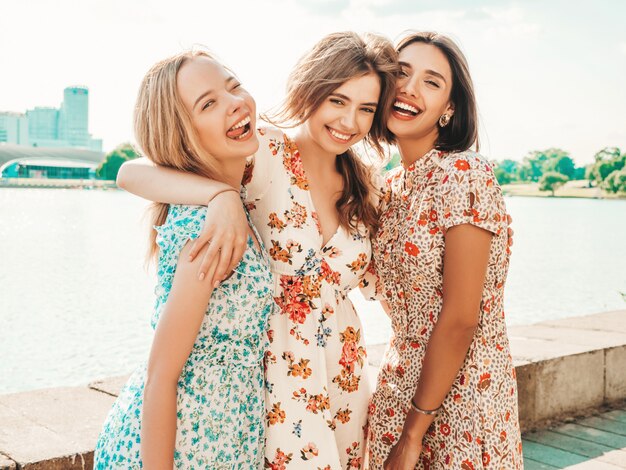 Drie mooie lachende meisjes in trendy zomer sundress poseren op straat