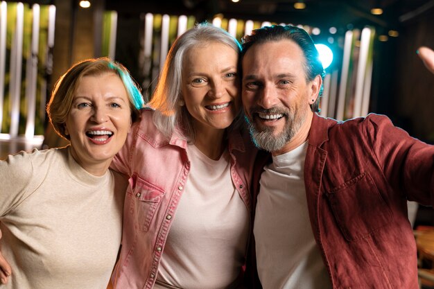 Drie oudere vrienden nemen een selfie in een restaurant.