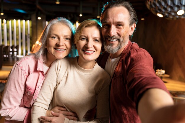 Drie oudere vrienden nemen een selfie in een restaurant.