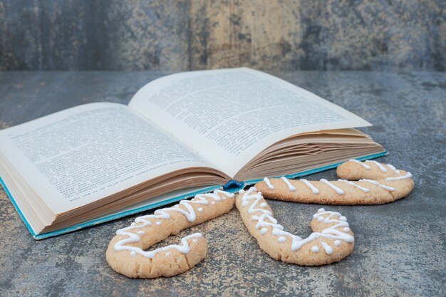 Drie peperkoekkoekjes en open boek over marmeren achtergrond. Hoge kwaliteit foto