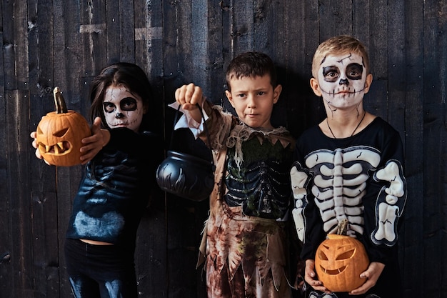 Gratis foto drie schattige kinderen in enge kostuums tijdens halloween-feest in een oud huis. halloween-concept.