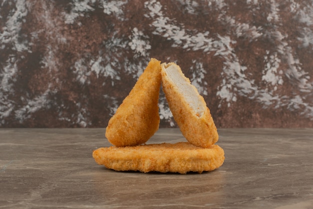 Gratis foto drie smakelijke kipnuggets op marmeren tafel.