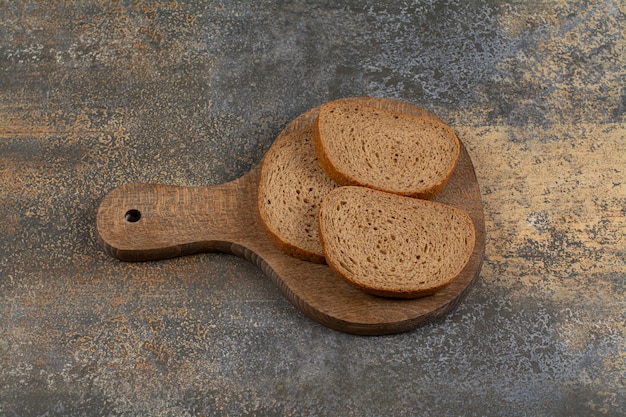 Drie sneetjes brood op een houten bord.