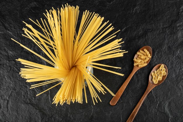 Drie soorten ongekookte pasta op een zwarte tafel.