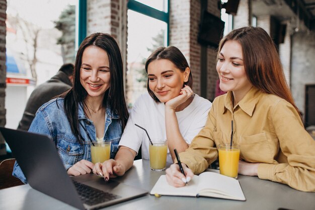 Drie studenten examen voorbereiden met laptop in een café