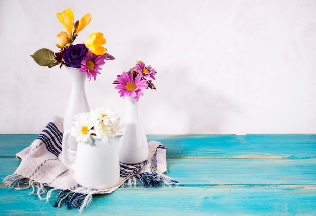 Drie vazen met heldere bloemen op tafel