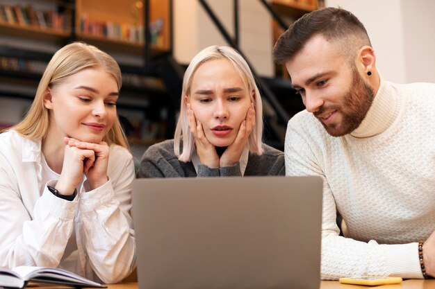 Drie vrienden studeren in een bibliotheek met een laptop