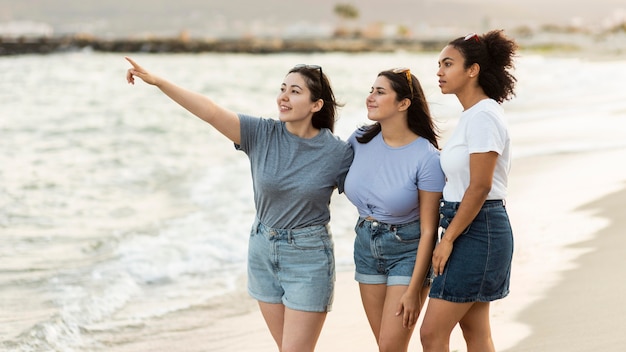 Drie vriendinnen die het uitzicht op het strand bewonderen