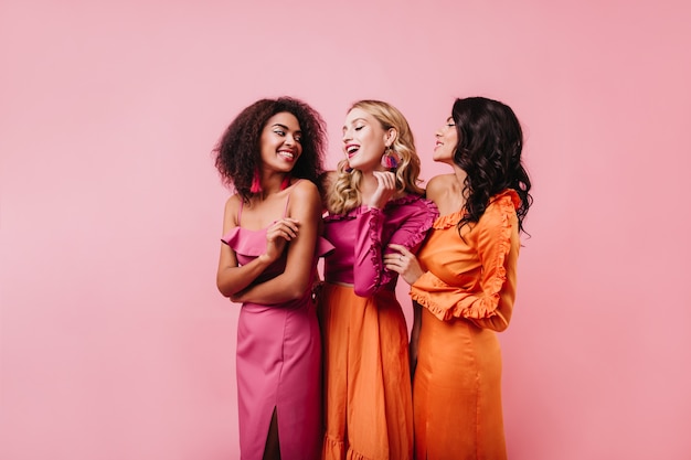 Drie vrouwen die op roze muur dansen