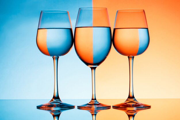 Drie wijnglazen met water over blauwe en oranje muur